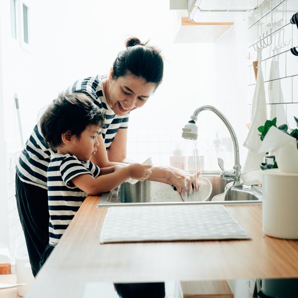 mother washing dishes with son at sink