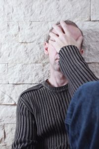 A boy covering his face and seating